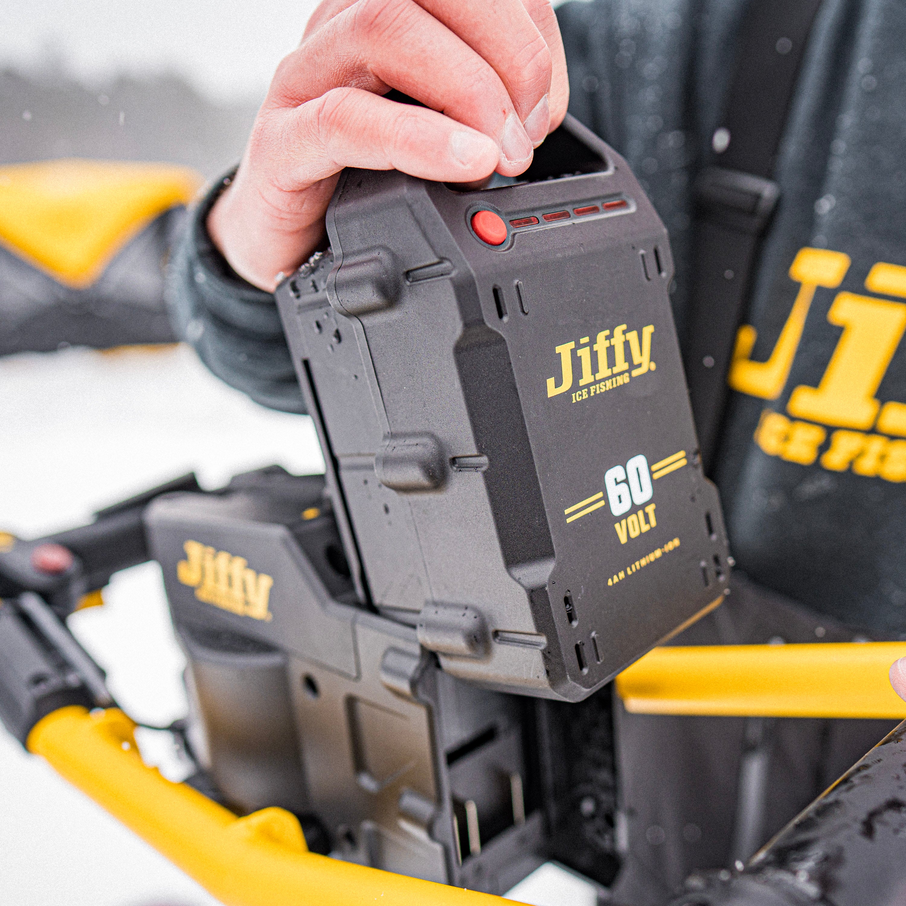 Jiffy 60-volt battery pack being removed from powerhead by a person with a blurred background