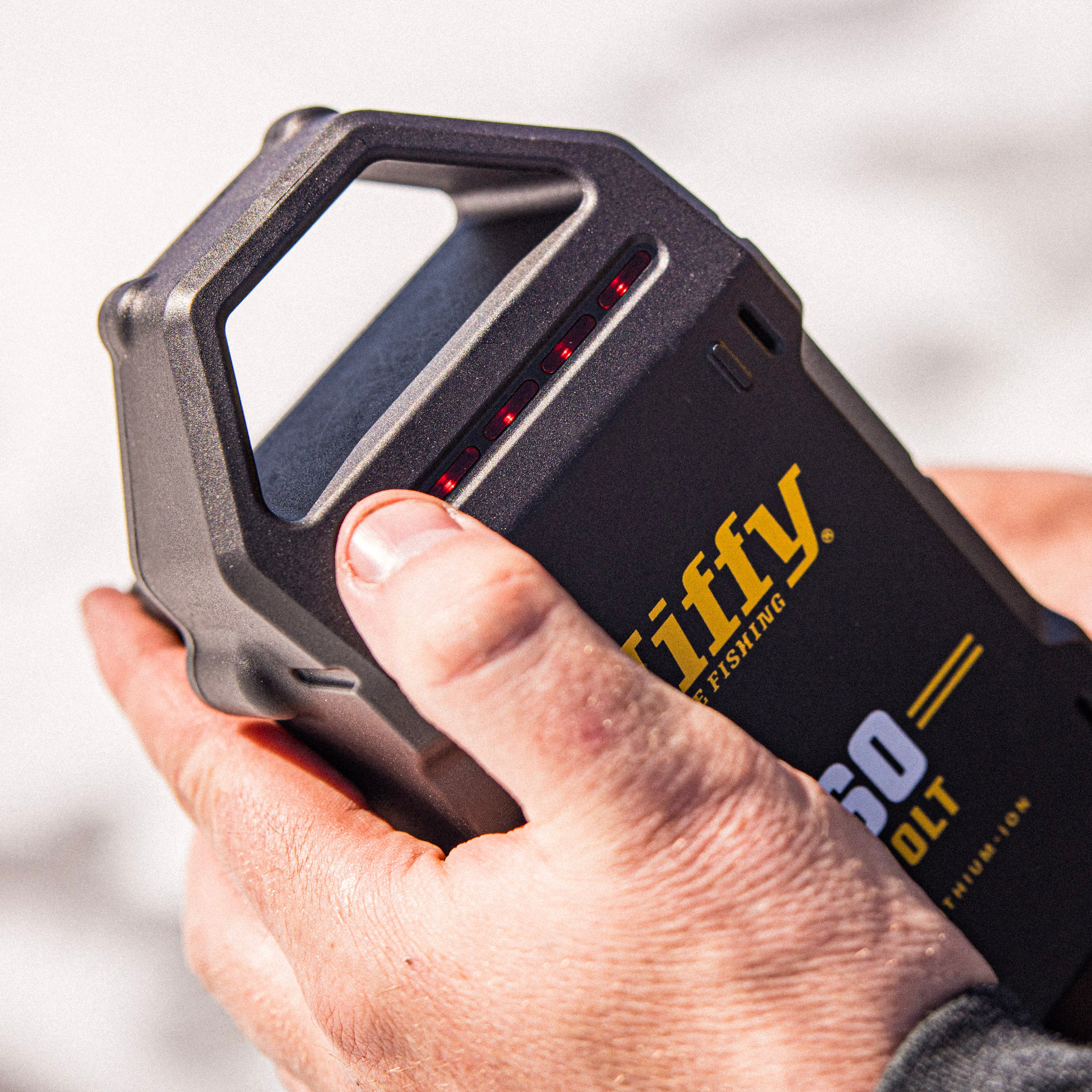 Hand holding a 60V battery with 'Jiffy' branding on a blurred background
