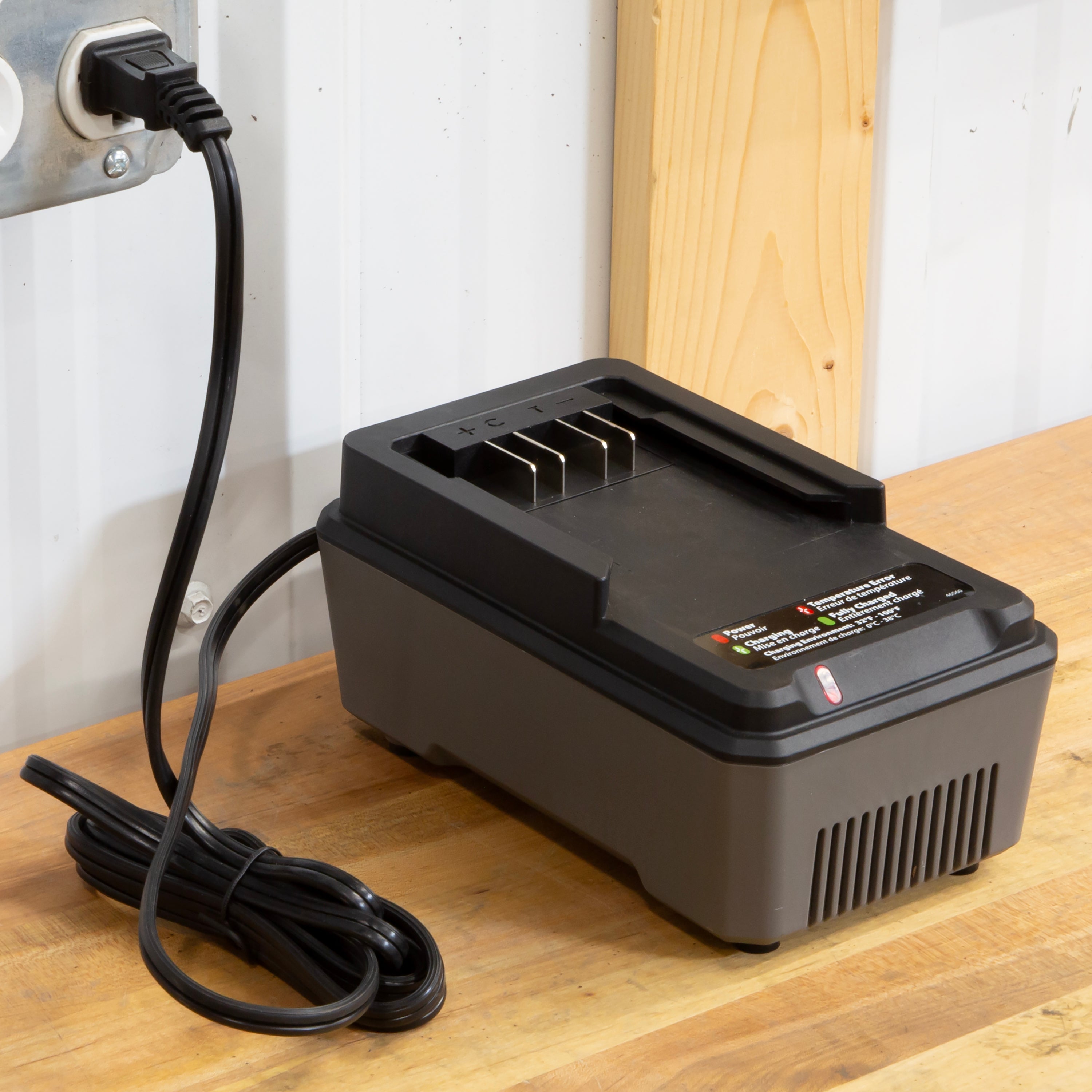 Black battery charger with power cord on a wooden surface