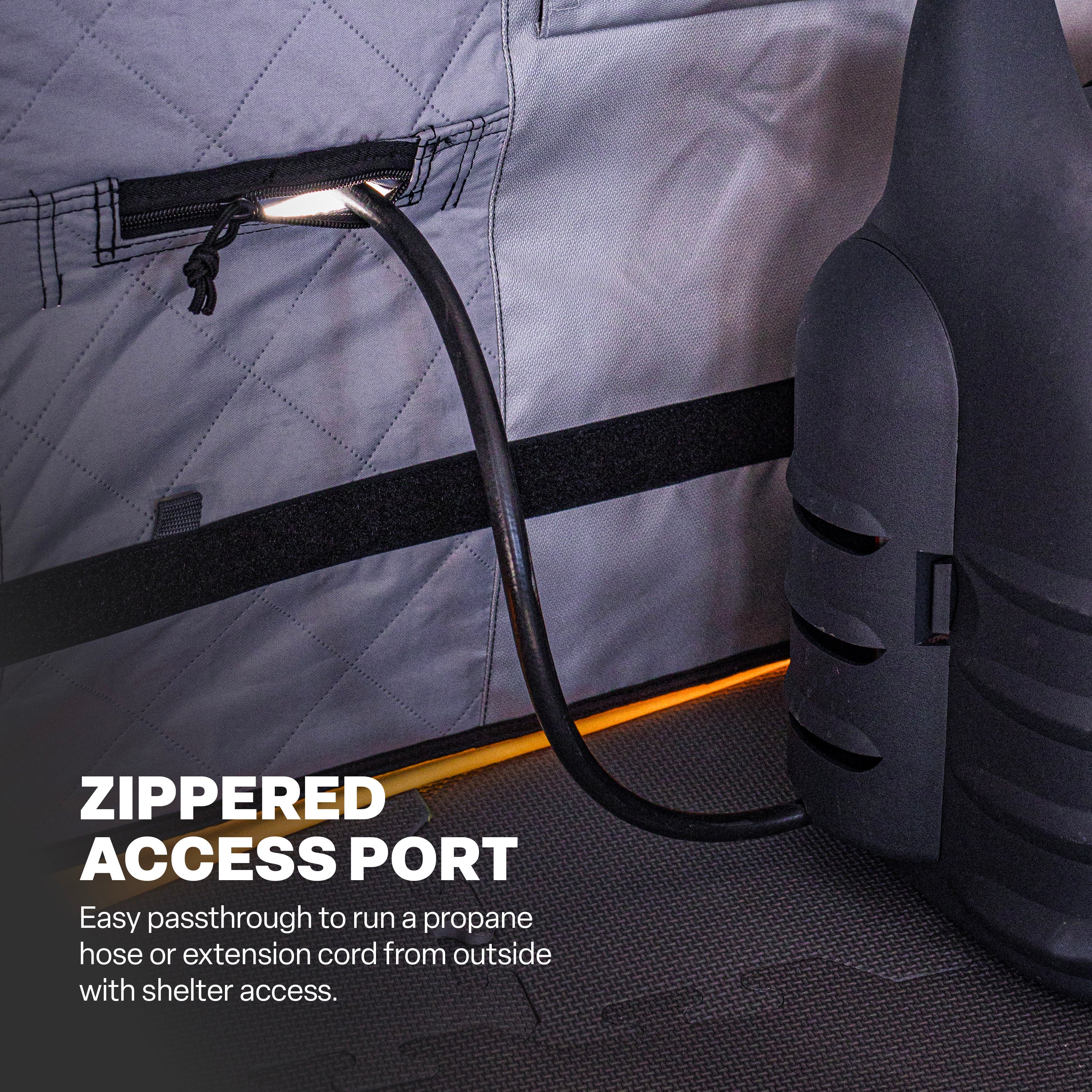 Zippered access port on the lower wall of a Basecamp™ shelter with a hose running through it.